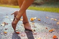 Close up of female shoes. Woman wears stylish brown high-heeled shoes in autumn park standing among falling leaves. Royalty Free Stock Photo