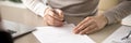 Close up female sitting at table holding pen signing contract