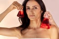 Close-up of female studio portrait of gorgeous young woman with glass flasks with red liquid. Charming girl with clear skin and Royalty Free Stock Photo