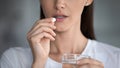 Cropped closeup image woman taking pill holding glass of water