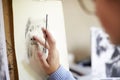 Close Up Of Female Teenage Artist Sitting At Easel Drawing Picture Of Dog From Photograph In Charcoal