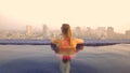 CLOSE UP: Female tourist observing the city in Vietnam from the rooftop pool. Royalty Free Stock Photo