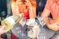 Close-up female waiter holding bottle of white champagne or prosecco for romantic couple dating on bright summer day. Girls hen- Royalty Free Stock Photo