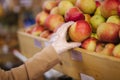 Close-up of females hand in protective gloves hold beautiful fresh apple in hand. Shopping during quarantine