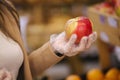 Close-up of females hand in protective gloves hold beautiful fresh apple in hand. Shopping during quarantine