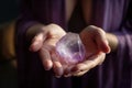 Close up of feminine hands holding beautiful amethyst crystal for meditation, natural purple color, view from the top