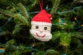 Close-up of a festive crocheted Santa Claus ornament hanging from the branch of a Christmas tree Royalty Free Stock Photo