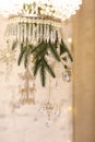 Close up of festive crystal ceiling chandelier decorated glass snowflakes, shiny gold baubles and green fir branches Royalty Free Stock Photo