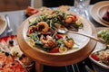 Close up festive table with fresh salad with grill seafood, greens and tomatoes on plate on wooden stand. Banquet table Royalty Free Stock Photo