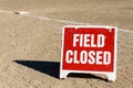 Close up of Field Closed sign on empty local baseball field, third base and baseline, on a sunny day