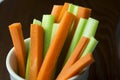 Close up filled frame isolated shot of party snack food. A white bowl of crunchy orange carrot and juicy green celery sticks on a Royalty Free Stock Photo