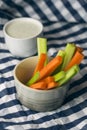 Close up filled frame shot of a bowl of party snack in form of orange carrot and green celery sticks with a white cup of blue Royalty Free Stock Photo