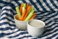 Close up filled frame shot of a bowl of party snack in form of orange carrot and green celery sticks with a white cup of blue Royalty Free Stock Photo