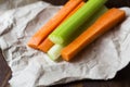 Close up filled frame shot of party snack food. A bunch of crunchy orange carrot and juicy green celery sticks laying on a piece