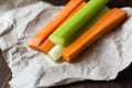 Close up filled frame shot of party snack food. A bunch of crunchy orange carrot and juicy green celery sticks laying on a piece