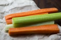 Close up filled frame shot of party snack food. A bunch of crunchy orange carrot and juicy green celery sticks laying on a piece