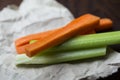 Close up filled frame shot of party snack food. A bunch of crunchy orange carrot and juicy green celery sticks laying on a piece