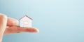 Close up of finger holding tiny house on wide background with mock up place for advert. Loan and insurance concept Royalty Free Stock Photo