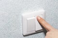 Close up. A finger presses down on a single white light switch on a wall. COPY SPACE Royalty Free Stock Photo