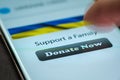 Close-up finger pressing donate button on smartphone screen. Donation money online concept