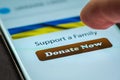 Close-up finger pressing donate button on smartphone screen. Donation money online concept