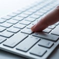 Close up of a finger pressing a key on a white computer keyboard Royalty Free Stock Photo