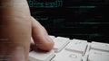 Close-up of a finger pressing a keyboard key with digital code overlay on a dark background, representing programming Royalty Free Stock Photo