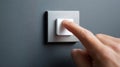 Close-up of a finger pressing a modern white light switch on a textured gray wall in a minimalistic interior setting Royalty Free Stock Photo