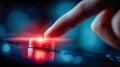 Close-up finger pressing a red emergency stop button on an industrial control panel with blue bokeh lights Royalty Free Stock Photo