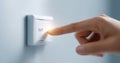 Close-up of a finger pressing a white switch labeled out on a light gray wall with soft lighting and shallow depth of field Royalty Free Stock Photo