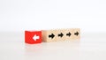 Close-up finger pushing arrow icon on cube wooden toy block stacked pointing to opposite direction