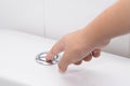 Close up of finger pushing a flush toilet button for cleaning. - Royalty Free Stock Photo