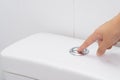 Close up of finger pushing a flush toilet button for cleaning. - Royalty Free Stock Photo