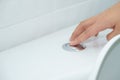 Close up of finger pushing a flush toilet button for cleaning. - Royalty Free Stock Photo