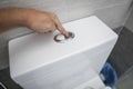 Close up of finger pushing a flush toilet button for cleaning a toilet. Royalty Free Stock Photo