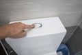 Close up of finger pushing a flush toilet button for cleaning a toilet. Royalty Free Stock Photo