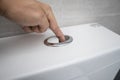 Close up of finger pushing a flush toilet button for cleaning a toilet. Royalty Free Stock Photo