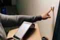 Close-up finger of unrecognizable delivery man ringing doorbell of customer apartment holding cardboard box, contactless