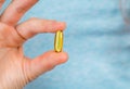 Close-up of fingers holding a fish oil capsule. Royalty Free Stock Photo