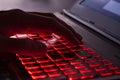 Close up of fingers typing on glowing red backlight keys on a computer keyboard. in the dark. Computer hacker, internet fraud or s