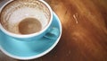 Close up, finished cup of hot cappuccino or hot latte coffee with leftover latte art, put on natural brown wooden board table