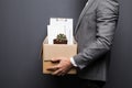 Close up of fired man employee hiding behind box with personal items on grey background Royalty Free Stock Photo