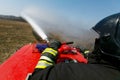 A firefighter puts out a hot field with a water cannon.