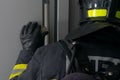 Close-up of a firefighter, rear view, looking out the dark window of a metal door, leaning on his arm Royalty Free Stock Photo