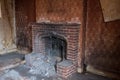 Close up of fireplace in derelict house, with wallpaper peeling off the wall. Harrow UK