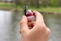 Close-up - fishing rod, line and red and white float in hand. River and forest in the background
