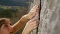 CLOSE UP: Fit female lead climber holds on to a flake grip on a massive cliff. Royalty Free Stock Photo