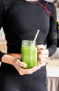 Close up of a fit woman in black sportswear holding a jar of green smoothie Royalty Free Stock Photo