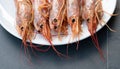 Close up of five giant prawns, in a white plate, on a slate table..Tasty food from italian cuisine and mediterranean sea. Concept