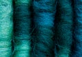 Close-up of five merino wool rolags, in colours green, turquoise, and blue